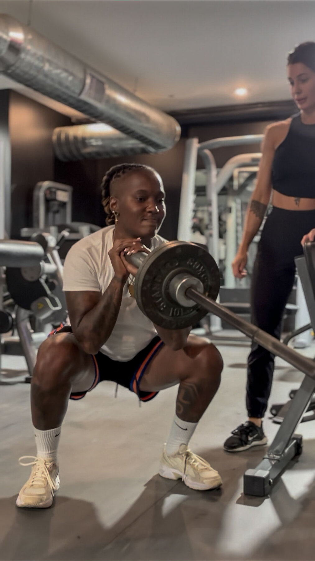Member front-squatting with coach watching form